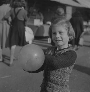 Ein kleines Mädchen mit einem Luftballon auf einer Kleinmesse