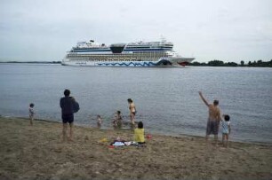 Auslaufendes Kreuzfahrtschiff AIDA Luna. Badegäste am Strand von Blankenese winken den Reisenden zu. Hamburg, 07.2013