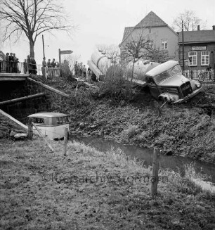 Verkehrsunfall: Kalkgraben: bei Einmündung in Hamburger Chaussee / B 75 und Brücke über Heilsau: Zementlastwagen mit Anhänger schräg auf Uferböschung: Wäscherei-Lieferwagen in Heilsau: rechts oben Eckhaus Gasthof "Kalkgraben": links oben an Brückengeländer Zuschauer, Baum, Wegweiser: im Vordergrund Wiese, Zaun