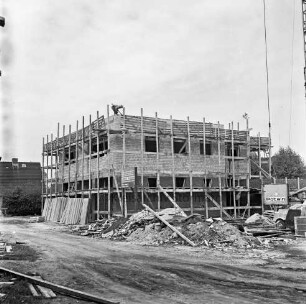 Bürgerhaus und Feuerwehrgerätehaus: Rohbau mit Gerüsten: davor Baumaterial und Baumaschinen: links oben auf Dach Arbeiter: links hinten Wohnhaus