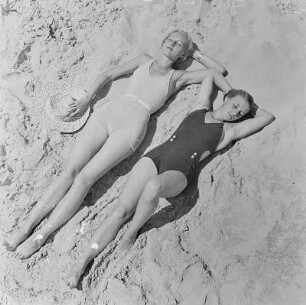 Zwei Frauen in Bademode liegen am Strand