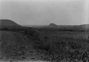 Stufenlandschaft : Blick auf Grasland rechts, eine Straße links am Bildrand verlaufend und einer Landstufe links im Hintergrund.