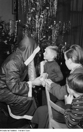 Weihnachtsmann beim Überreichen von Geschenken an Kinder auf der Weihnachtsfeier des VEB Kartographie