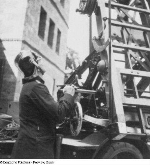 Feuerwehrmann am Getriebe einer Automobildrehleiter (Aufrichten der ausgefahrenen Leiter)