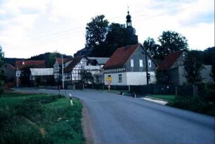 Straße mit Häusern, hinten Ortsschild