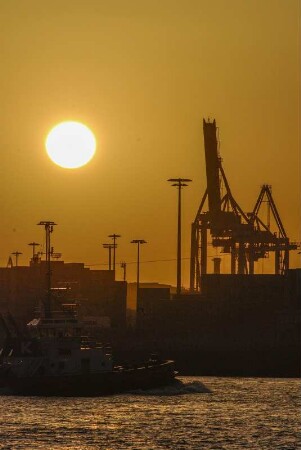 Sonnenuntergang vor der Skyline eines Container-Terminals im Hamburger Hafen