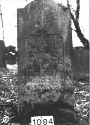 Grabstein 1084 (Index: 99899730) Material: Sandstein Zustand: fast völlig verwittert Maße HxBxT: 128x55x10 cm Beschreibung: Stele mit eingezogenem Rundbogenabschluss Besonderheit: vermutete Identifizierung nach Gräberverzeichnis: Grabstein 1084