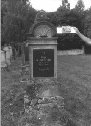 Grabstein 56 (Index: 99609692) Material: Sandstein Zustand: Mittelaufsatz fehlt, Schriftplatte vermutlich erneuert Maße HxBxT: 182x64x31 cm Beschreibung: Stele, Abdeckplatte, Aufsatz mit eingezogenem Rundbogenabschluß, im Bogen Muschelwerk, Verdachung, Mittelerhöhung, Aufsatz fehlt, rechteckige Schriftplatte eingelassen, getreppter Sockel, unten Rusticaimitat Besonderheit: Schriftplatte vermutlich ersetzt; - Kindergrab: Grabstein 56