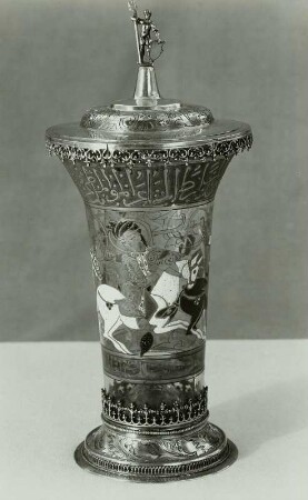 Syrischer Glasbecher mit zwei arabischen Schriftfriesen (oben alte Naskbi-Schrift, unten kursiv wiederholt), dazwischen 3 reitende Polospieler, auf Deckel antiker Krieger
