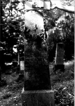 Grabstein 53 (Index: 100109288) Material: Sandstein oder Marmor (?), Sockel Kalkstein Zustand: leicht verwittert Maße HxBxT: 163x46x46 cm Beschreibung: Obelisk, getreppter Sockel Symbolik: Blumengirlande Steinmetz: Beerli Besonderheit: Nummer auf Rückseite: 151: Grabstein 53