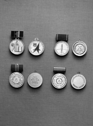 Medaillen der Deutschen Demokratischen Republik (DDR). Oben links: Medaille für hervorragende Leistungen in der Bewegung Messen der Meister von morgen. Version 1969/1975 (Bronze; 31,5 mm Durchmesser; 1969 gestiftet) an Spange (blau emailliert; 13,5 x 25,5 mm). Oben rechts: Medaille für treue Dienste in der zivilen Luftfahrt (50 mm Durchmesser; 192 gestiftet) an Spange (blau bezogen). Unten links: Medaille für Verdienste in der Rechtspflege, verliehen in drei Stufen (30 mm Durchmesser; 1965 gestiftet) an Spange (fünfeckig, rot bezogen; 12 x 24 mm). Unten rechts: Erinnerungsmedaille 20. Jahrestag der Bodenreform - demokratische Bodenreform (vergoldet; 31,5 mm Durchmesser; 1965 gestiftet) an Spange (bezogen; 12 x 24 mm). Jeweils Avers und Revers