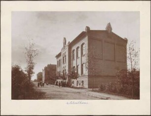 Schulhaus, davor Schülerinnen.