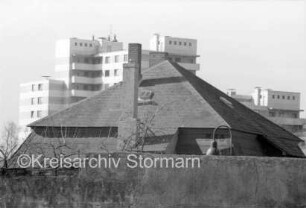 Raiffeisen-Passage: Blick auf Hochhaus: im Vordergrund Häuserdächer, Straßenlaterne und Äste