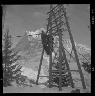 Handwerker auf einem Strommast im Berner Oberland.
