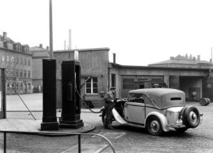 Deutsche Reichspost. Instandsetzungswerkstatt für Postkraftwagen. Diensttankstelle hinter der Einfahrt, Fahrer beim Betanken eines Personenkraftwagens : Dresden-Friedrichstadt, Löbtauer Straße 80. Deutsche Reichspost. Instandsetzungswerkstatt für Postkraftwagen. Diensttankstelle hinter der Einfahrt, Fahrer beim Betanken eines Personenkraftwagens