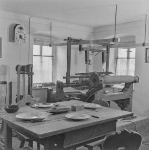 Rat des Kreises : Oberlausitz. Unbekannter Ort, Museum. Raumaufnahme mit einer Webmaschine und einem gedecktem Tisch