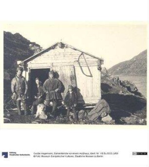 Samenfamilie vor einem Holzhaus