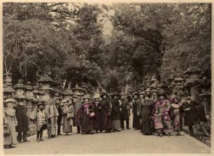 Nara, Japan. Gruppenbild mit Touristen und Einheimischen auf einem mit steineren Heiligen Laternen gesäumten Weg des Nara-Parks