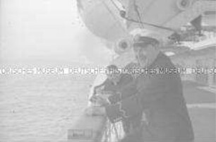Lachender Offizier an Bord des Hochseepassagierdampfers "Bremen", an der Reling unter einem Rettungsboot stehend