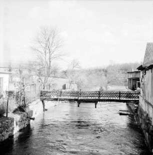 Trave: Stadtarm: hinten Fußgängerbrücke: rechts und links Häuser und Gärten