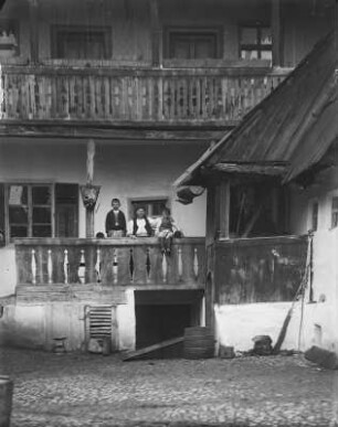 Familie auf Balkon : Blick in einen Hof. Auf einem Balkon eine Mutter mit zwei Kindern.