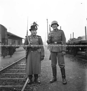 Ein deutscher und ein ungarischer Soldat an einer Bahnstrecke