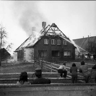 Brand: Reetdachhaus auf Nachbarhof Holm: Funkenflug vom Brand des Hofes von Walter Ellerbrock: brennendes Dach: links Feuerwehrmänner beim Löschen: im Vordergrund Zuschauer