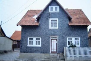 kleines, verschiefertes Haus mit Zwerchgiebel; Vorgarten