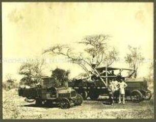 Kolonialoffizier mit Afrikanern bei Lastkraftwagen