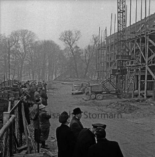 Amtsgericht: Weg zum Bürgerpark: Neubau: Richtfest: eingerüsteter Rohbau: davor Baumaschine, Aufzug und Pkw: vorn links Ehrengäste und Arbeiter: hinten Bäume des Parks