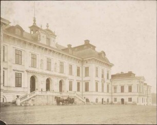 Hauptportal eines Schlosses, davor zweispännige Kutsche.