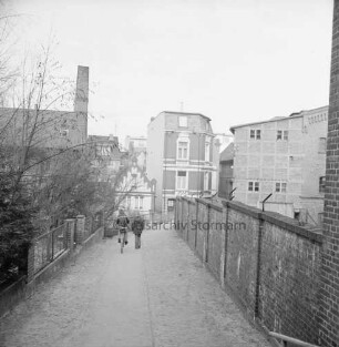 Mühlengang: darauf zwei Kinder, eins auf Fahrrad: Blick Richtung Hindenburgstraße: hinten rechts ehemalige Kornwassermühle: hinten Mitte Wohnhäuser: hinten links ehemaliges Fabrikgebäude