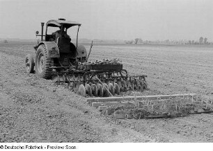 Bauer mit Traktor beim Pflügen eines Feldes