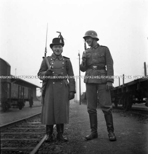 Ein deutscher und ein ungarischer Soldat an einer Bahnstrecke