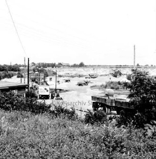 Kiesgrube: Blick von oben in die Grube: Kiesabbau: rechts und hinten Kiesanhänger: links Gebäude: hinten Förderanlagen: im Hintergrund Wohnhäuser