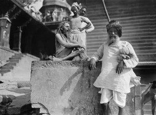 Varanasi (Benares), Indien. Heiliger Mann (Sadhu) auf einem Stein vor Tempelaufgang sitzend