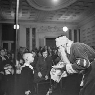 Kleiner Junge steht vor dem Weihnachtsmann, Kinderfest zur Weihnachtszeit