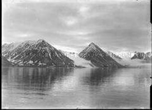 Dunkle Bergreihe mit Schneefurchen, Gletscher, Steilküste und spiegelglattem Fjord, Nordlandreise, Norwegen