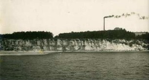 Bewaldete Steilküste mit Fabrikanlage