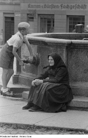 Porträt einer alten Frau an einem Brunnen