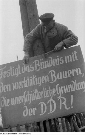 Anbringen eines Schildes mit politischer Propaganda für die DDR