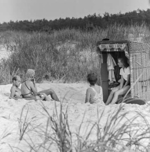 Menschen in Badebekleidung am Strand mit Strandkorb