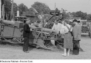 Ausstellungsbesucher an einem landwirtschaftlichen Gerät