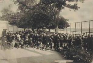 Ca. 100 Kriegsgefangene teils stehend, teils sitzend unter Bäumen im Spazierhof des Kriegsgefangenenlagers Hohenasperg