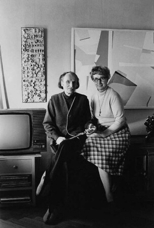 Der Maler Willy Wolff mit seiner Lebensgefährtin Gerda Dudeck in der Wohnung, im Hintergrund zwei seiner Werke