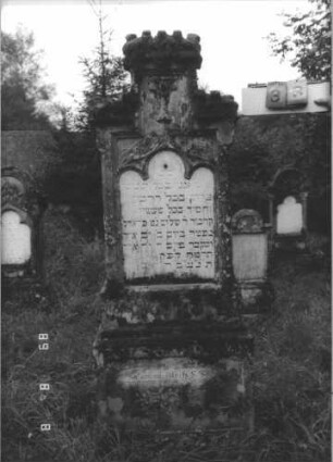Grabstein 33 (Index: 99800326) Material: Sandstein; Schriftplatte Marmor Zustand: verwittert Maße HxBxT: 188x60x19 cm Beschreibung: Stele mit Mittelerhöhung, Zinnenaufsatz, Schriftplatte eingelassen mit Kleeblattbogenabschluß, getreppter Sockel Symbolik: floral: Grabstein 33