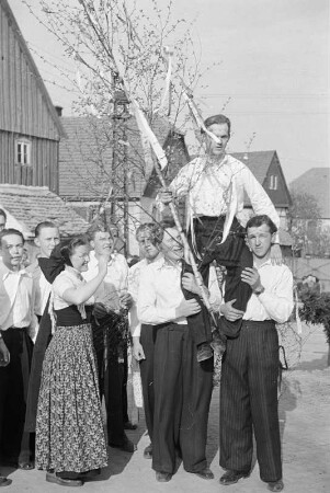 Der Maikönig beim Maibaumwerfen in Ostro : Mejemjetanje we Wotrowje. Młodźencaj njesu mejskeho krala na ramjenjomaj : Ostro / Wotrow