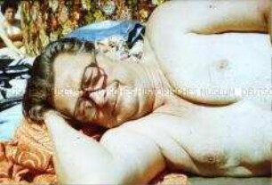 Dicker, älterer Mann mit Brille und nacktem Oberkörper liegt dösend in der Sonne (Altersgruppe 14-17)