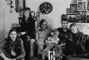 Familie K. im Wohnzimmer, an der Wand zahlreiche (Taschen)uhren