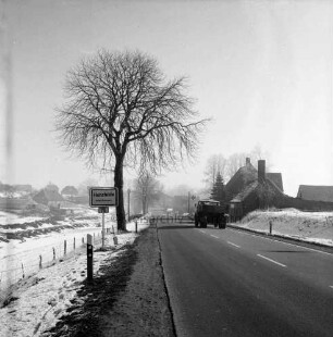 Stormarnstraße: Bundesstraße B 75 aus Richtung Hamberge: hinten rechts Lkw: links Ortseingangsschild: dahinter Bäume: im Hintergrund Wohn- und Bauernhäuser: Winter